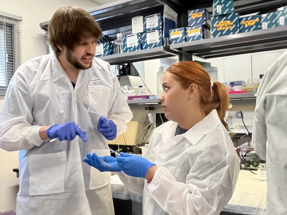 Tanner Padilla speaking with a student in lab coat