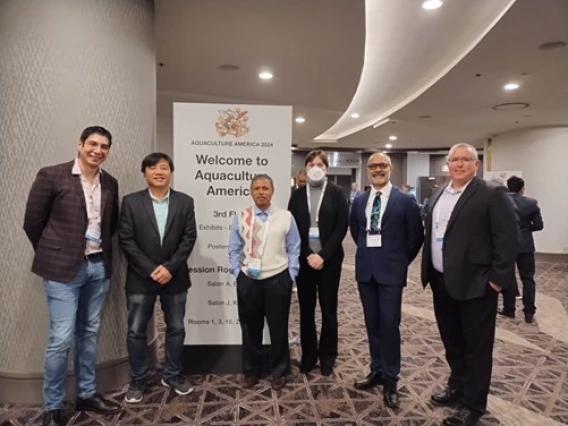 Roberto Cruz, Hung Mai, Arun Dhar, Maia Koliopoulos, Carlos Pantoja, and Paul Schofield stand in front of a sign for Aquaculture America 2024