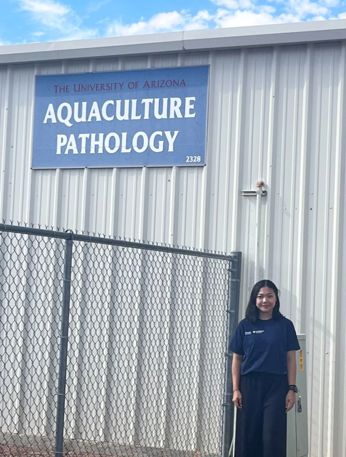 Dr. Magdalena Lenny Situmorang in front of a sign saying "Aquaculture Pathology"